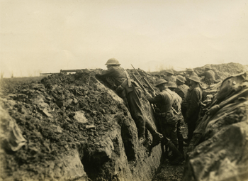 An archival photo of World War I soldiers standing in a trench, a ditch dug into the ground. 