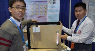 Sum Ming (“Simon”) Wong, 17 (left), and Kin Pong (“Michael”) Li, 18, of Hong Kong show off the self-sanitizing door handle they developed. It’s powered by opening and closing the door.