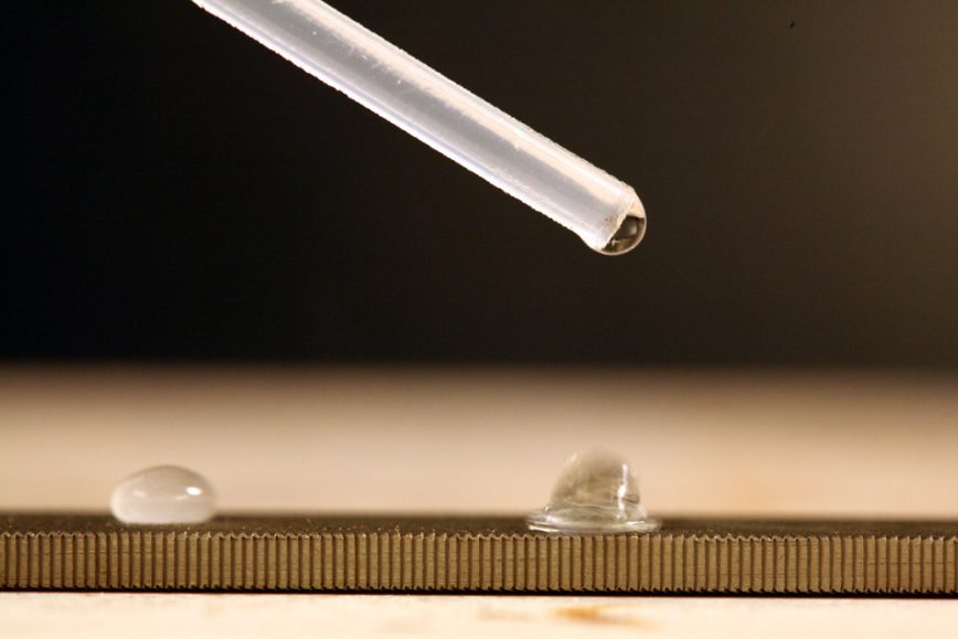 a close up of a pipette droping droplets of water
