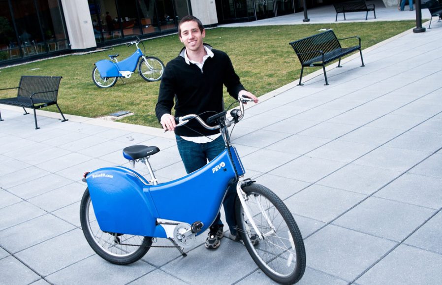 a man standing next to a blue electric bike