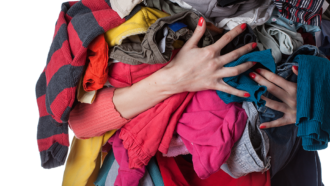 a pair of hands wearing nail polish and holding a load of laundry