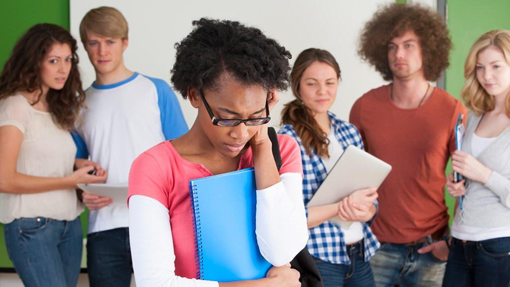 a photo of a mixed race girl feeling rejected by her peers standing behind her