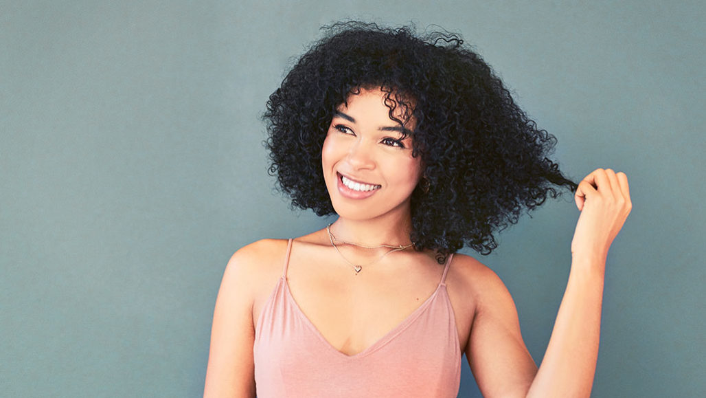 a young black woman with curly hair smiling