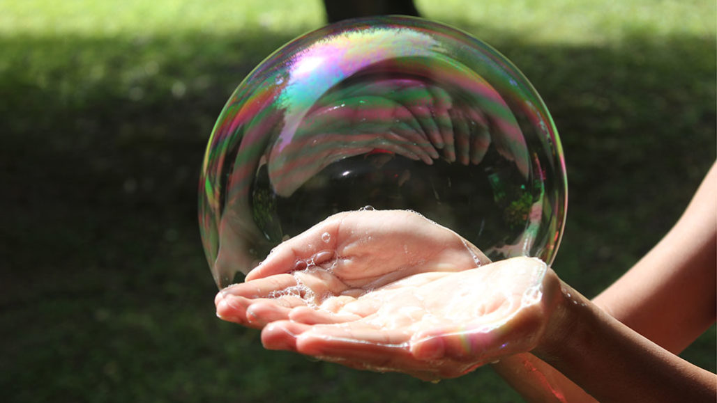 hands holding a large soap bubble