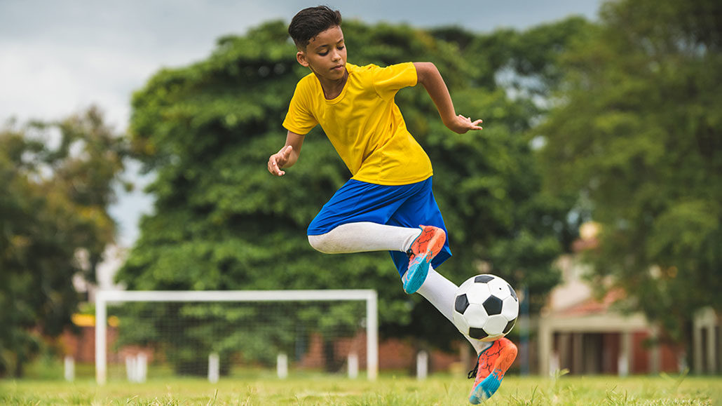 a photo of a kid running with a soccer ball on a field