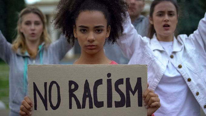 a photo of an african-american girl holding a sign that says "no racism"