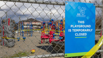 a picture of a playground fence with a sign reading "This playground is temporarily closed"