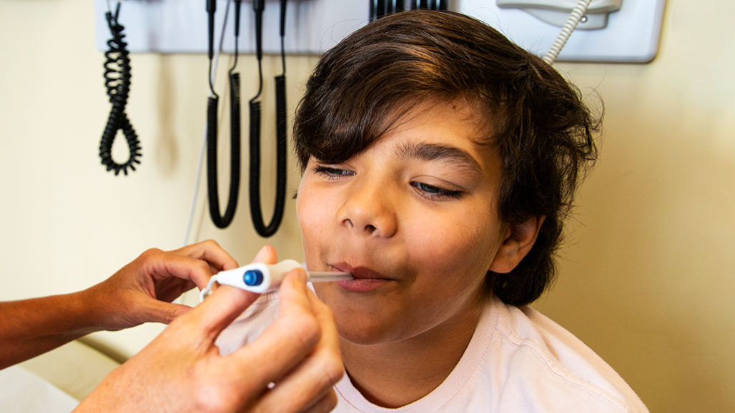 a photo of a young man getting his temperature taken in a doctor's office