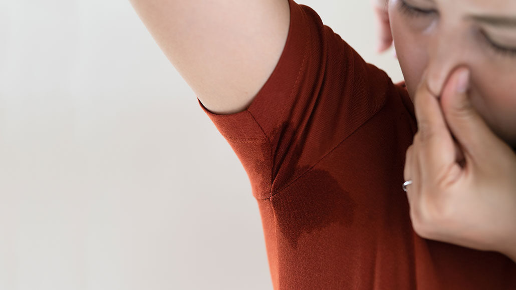a picture of a woman holding her nose and sniffing her sweaty armpit