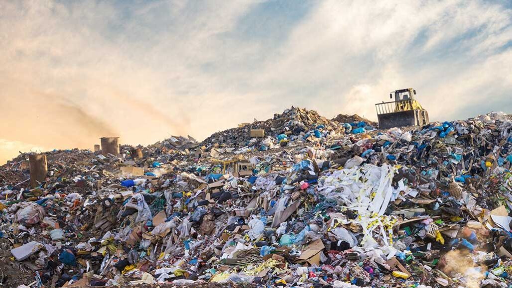 a photo of a bulldozer on top of a mountain of trash