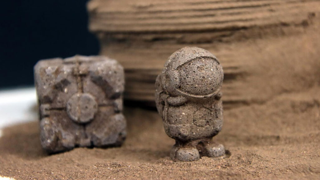 a companion cube and a tiny astronaut made out of mock Martian soil with a bit of chitin