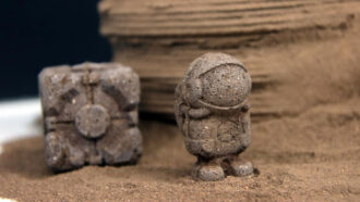 a companion cube and a tiny astronaut made out of mock Martian soil with a bit of chitin