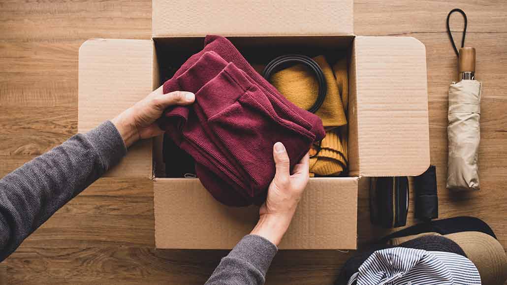 hands putting clothing in a box to give away