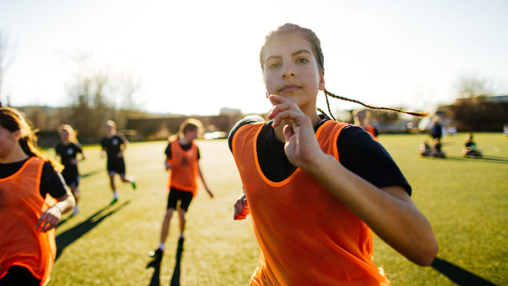 a girl with braids running on a soccer field