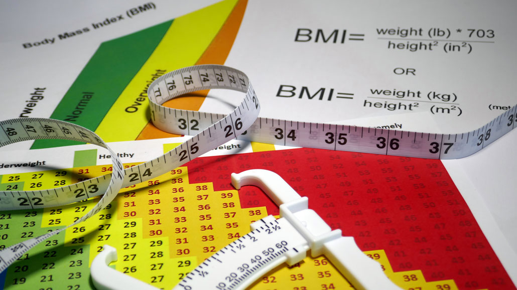 a photo of calipers, measuring tape and a BMI chart on a table