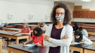a teacher weaing a fabric face mask and standing in front of her class
