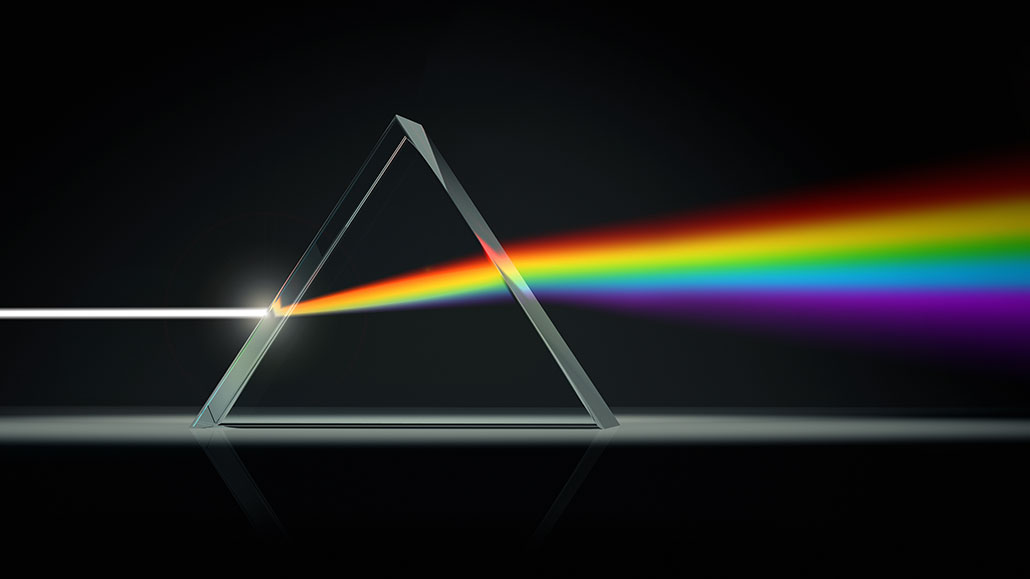 a photo of white light breaking into a rainbow after going through a triangular prism