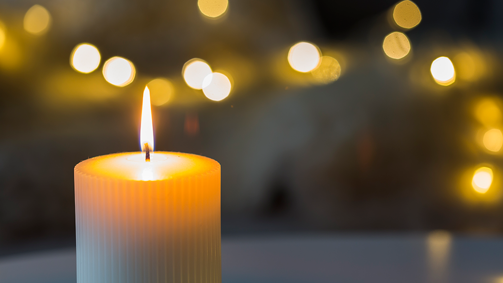 a photo of a lit candle in front of blurry background lights
