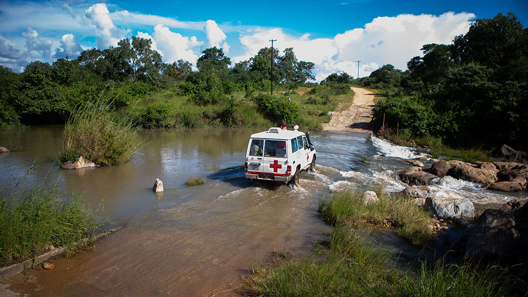 a van crossing a flooded bridge on a rural road