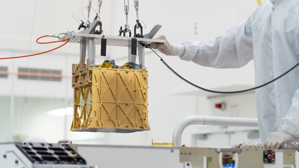 a person in a clean suit maneuvers a gold-colored cube