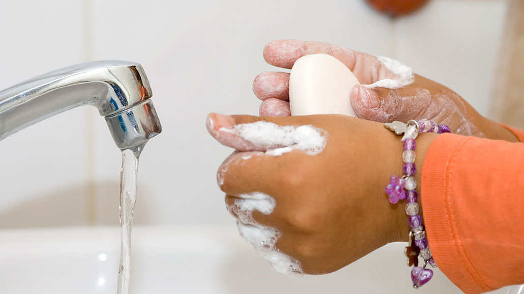 a photo of brown hands washing with soap and water
