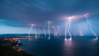 multiple lightning strikes seen striking at the horizon over water