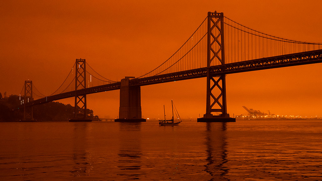 a photo of an orange sky behind a bridge