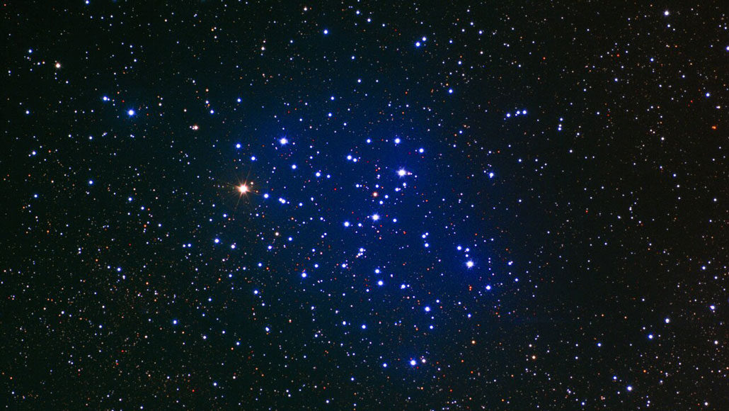 telescope image of a star cluster, which is surrounded by a blue haze