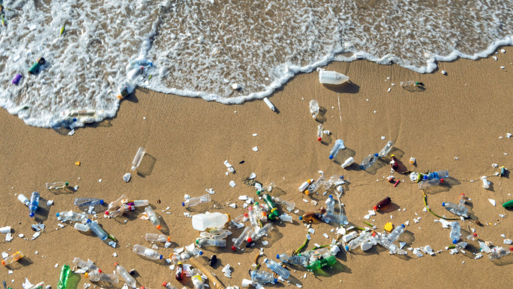 plastic trash collects on a beach near waves