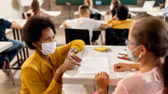 a teacher and student wear masks in a classroom