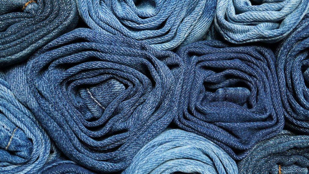 rolled up pairs of blue jeans of varying shades bunched together