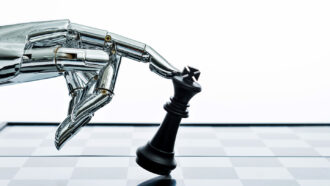 an image of a silver robot hand tipping over a black king chess piece on a glass board