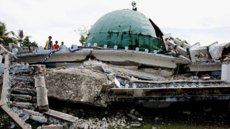 a mosque destroyed after an earthquake, several kids stand to the left