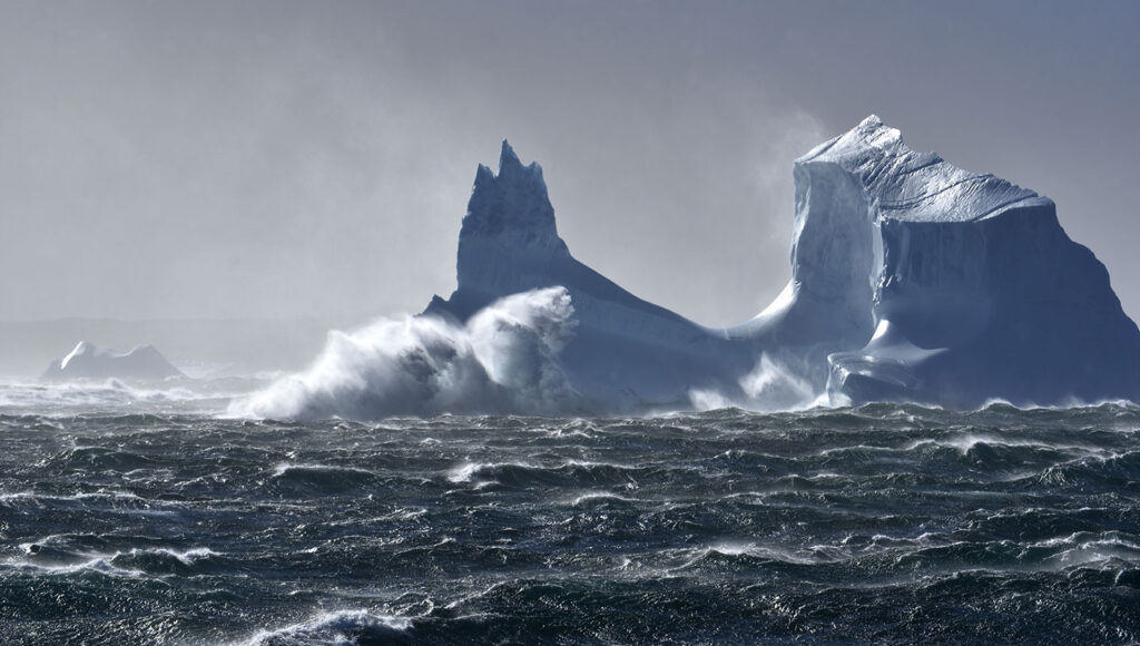 a photo of an iceberg on choppy seas