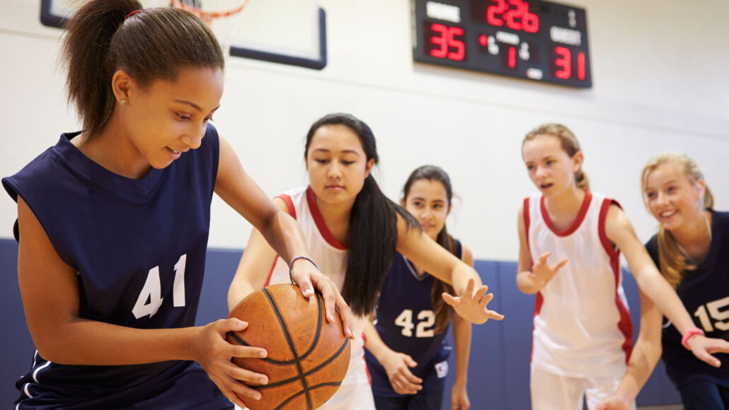 five middle-school girls play basketball
