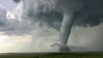 a huge tornado whirls across an open plain