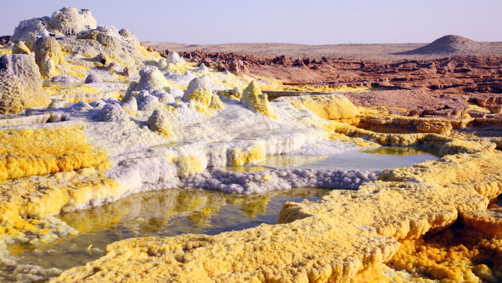 yellow and white salts crust the ground at a salt deposit in Ethiopia