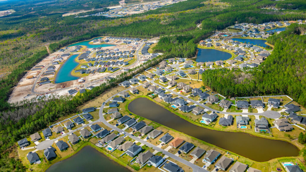 an aerial view of a suburb shows ponds built between housing developments