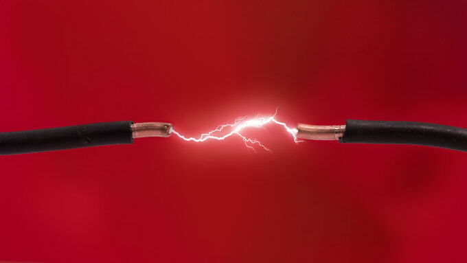 a photo of two copper wires with a gap between the ends of the wires. There is an electric spark jumping across the gap.