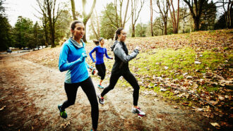 Three young women jog along a wooded path