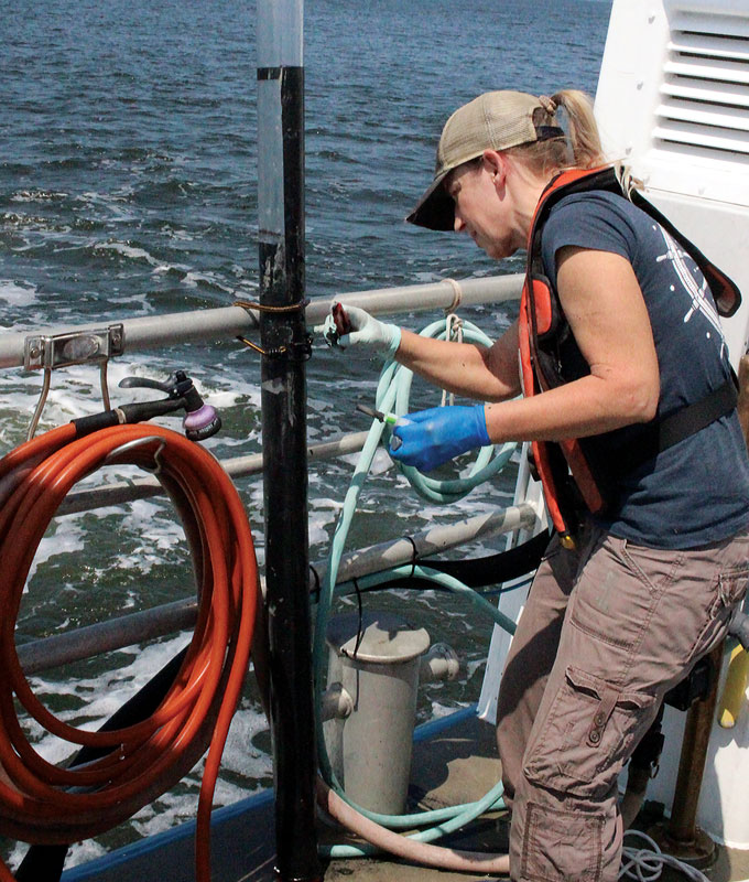 Sairah Malkin looks at a sediment core tube on a boat in the Chesapeake Bay