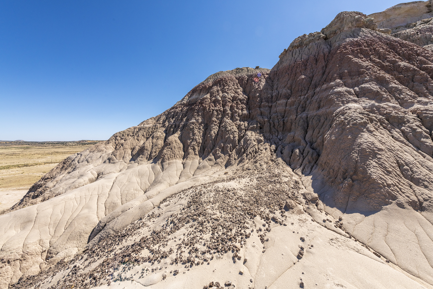 a rocky, sloping, desert-like terrain under a blue sky