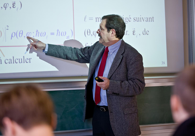 Alain Aspect points to an equation on a projector screen