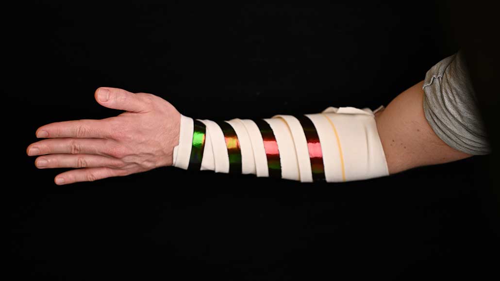 a photo showing a bandage wrapped around a person's forearm, the new material is wrapped around as well and varies in color according to how tightly it is stretched