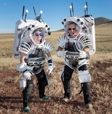 Um homem e uma mulher em um protótipo de um novo traje espacial de pouso lunar