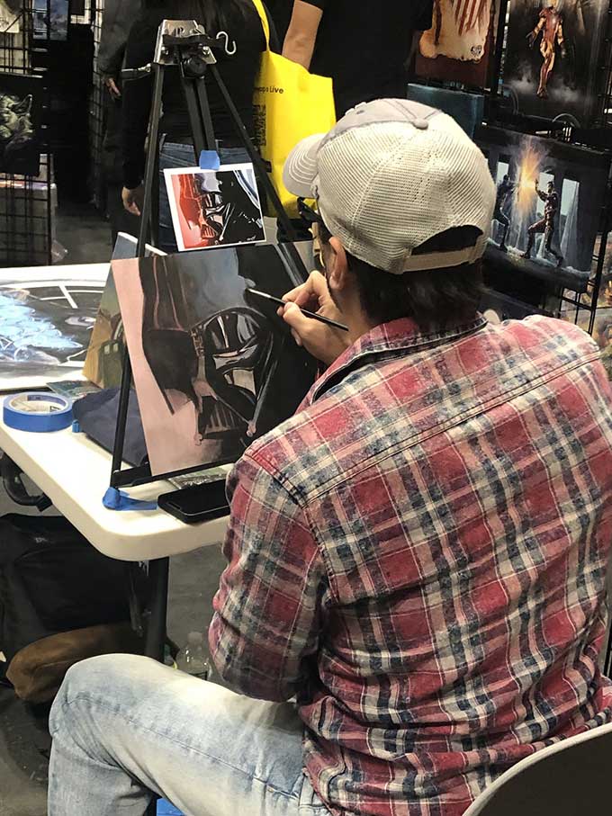 a artist is painting a portrait of Darth Vader