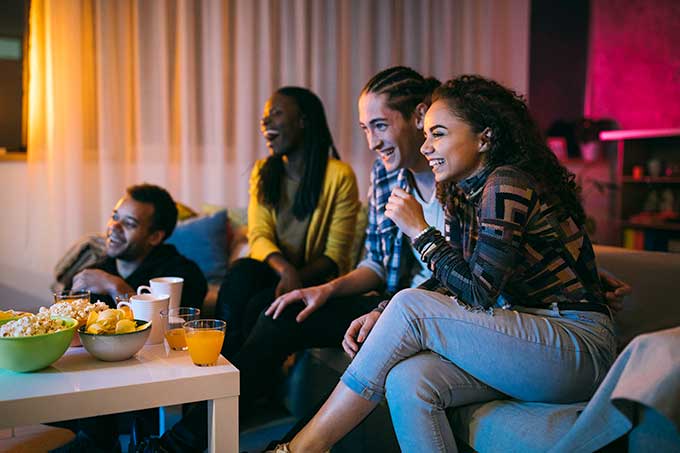 friends sitting and watching a show with plenty of snacks