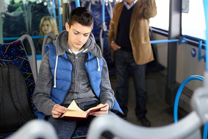a boy reading intently while riding a city bus