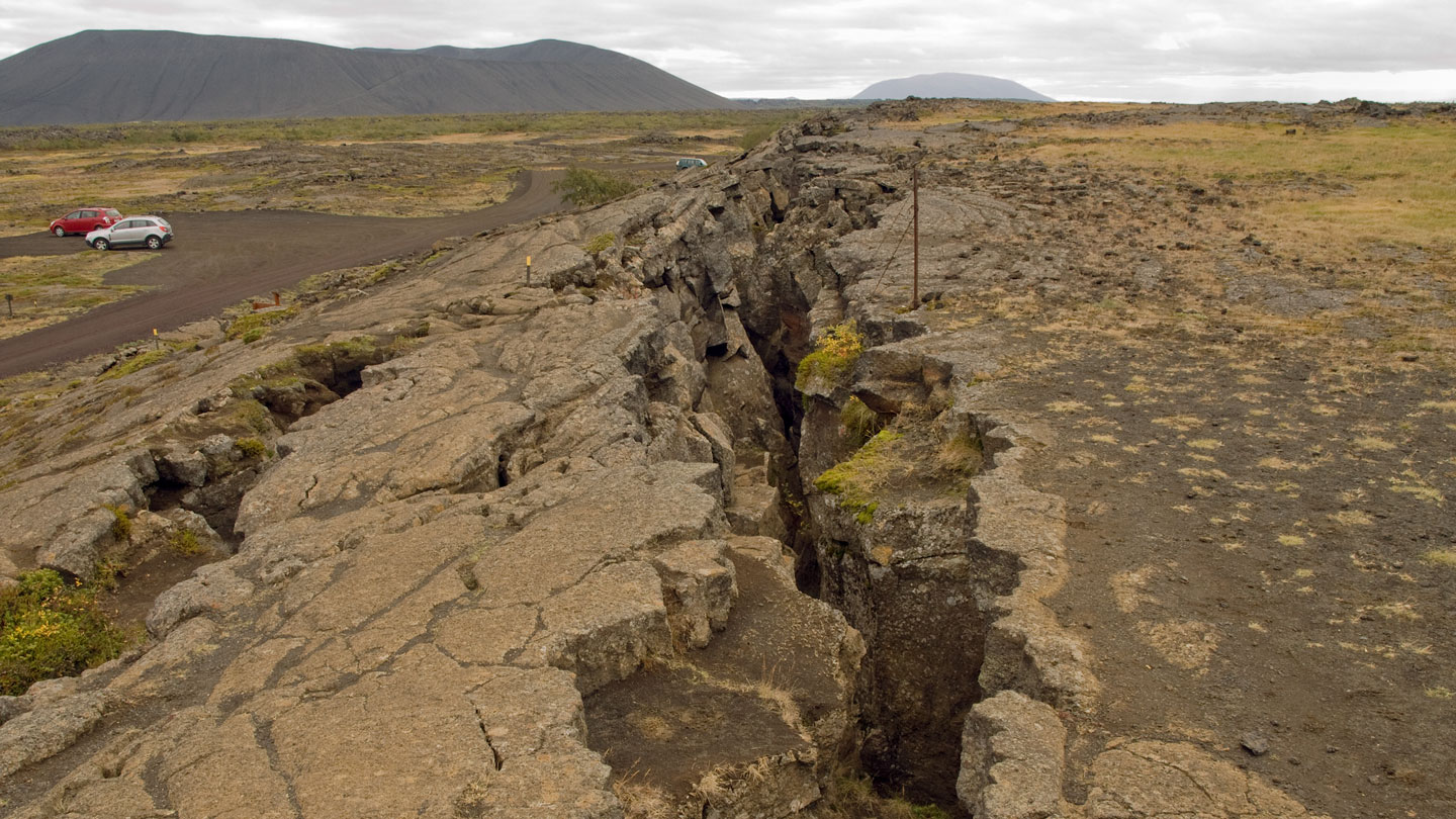 a huge crack runs down dry, brown terrain