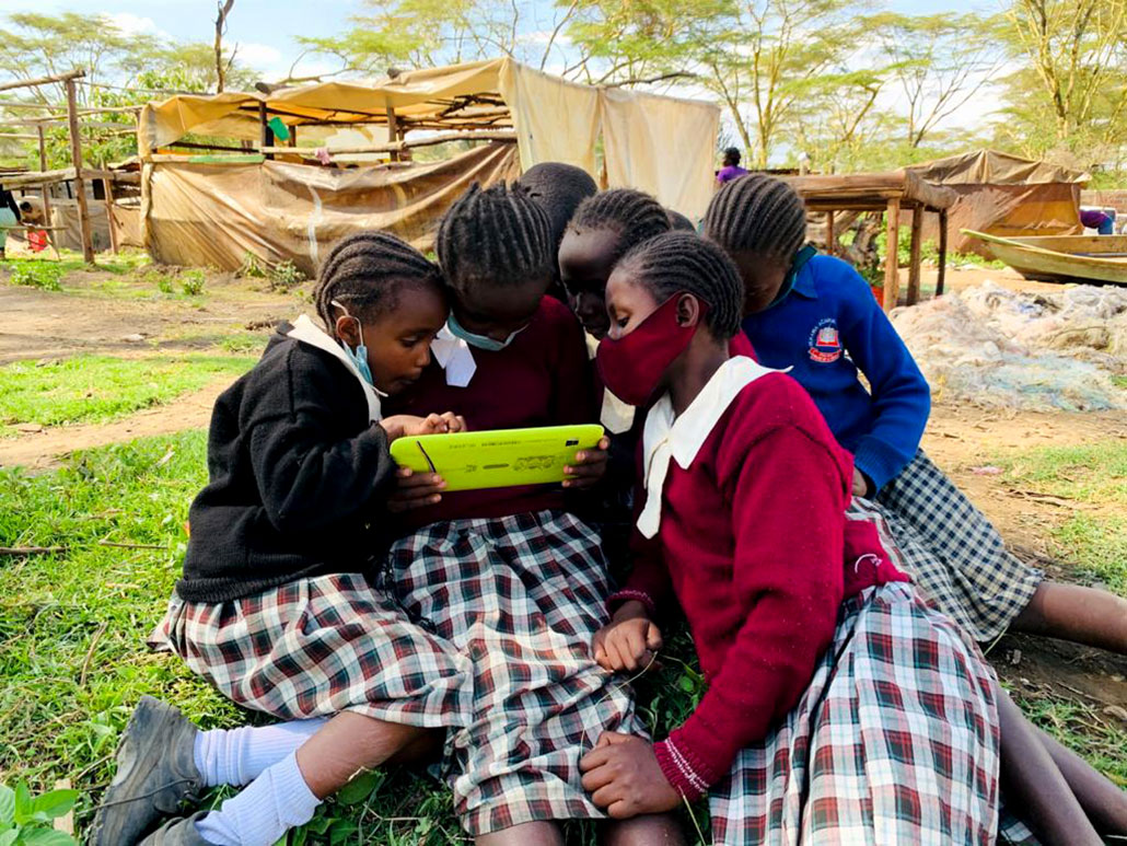 a group of Kenyan girls wearing school uniforms sit outside and huddle around a tablet  Will the internet soon reach the one-third of people without it?   1030 Internet for all Munga Kenya